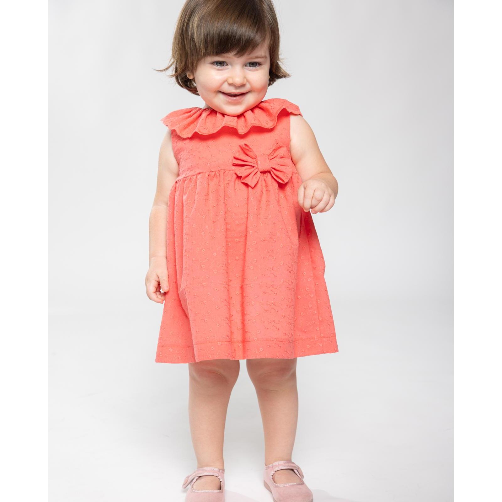 Vestido corto bordado coral, volante en el cuello y falda fruncida. Lazo en la cintura.