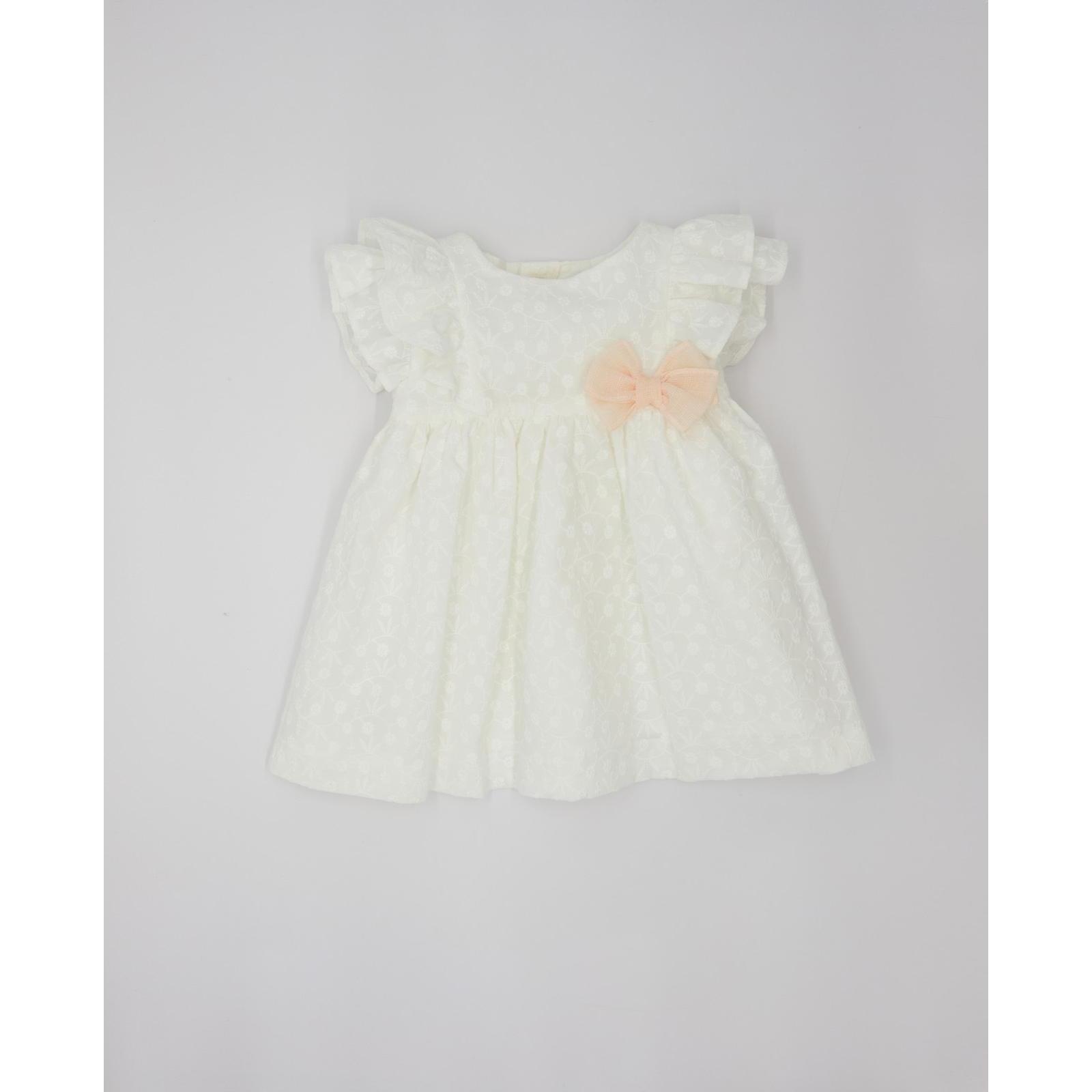 Vestido corto blanco bordado, volantes en la sisa y lazo rosa.