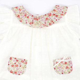 Blusa blanca con bolsillos y volante en el cuello de flores rojas, volantes en las sisas. Lazo en el bolsillo.