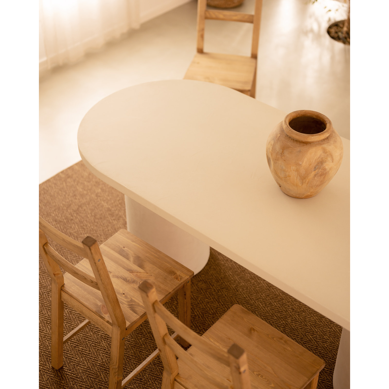Table de salle à manger ovale en microciment de teinte blanc cassé disponible en différentes tailles