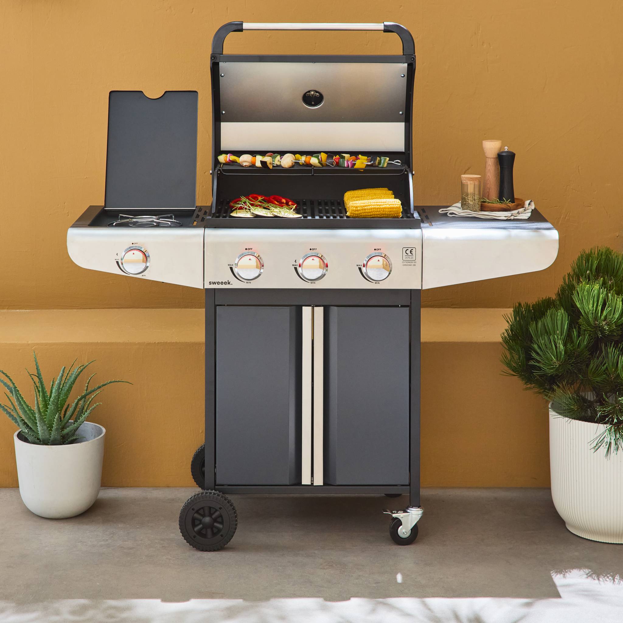 Barbecue au gaz - Bazin 3 Gris anthracite -  Cuisine extérieure 3 brûleurs + 1 feu latéral avec tablettes et thermomètre. rangement. roues