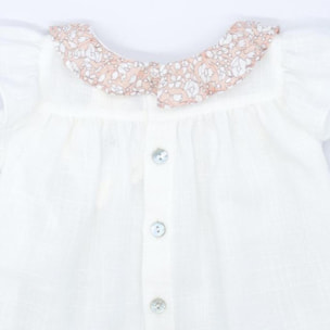 Blusa blanca con bolsillos y volante en el cuello de flores rosas, volantes en las sisas. Lazo en el bolsillo.