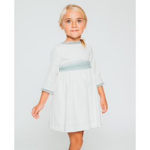 Vestido de pique blanco, con volantes en cuello y puños, y lazada en tul verde.