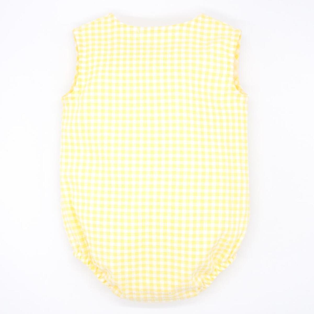 Pelele de vichy amarillo. Con bolsillo y tapeta con botones en el delantero. Goma en las piernas.