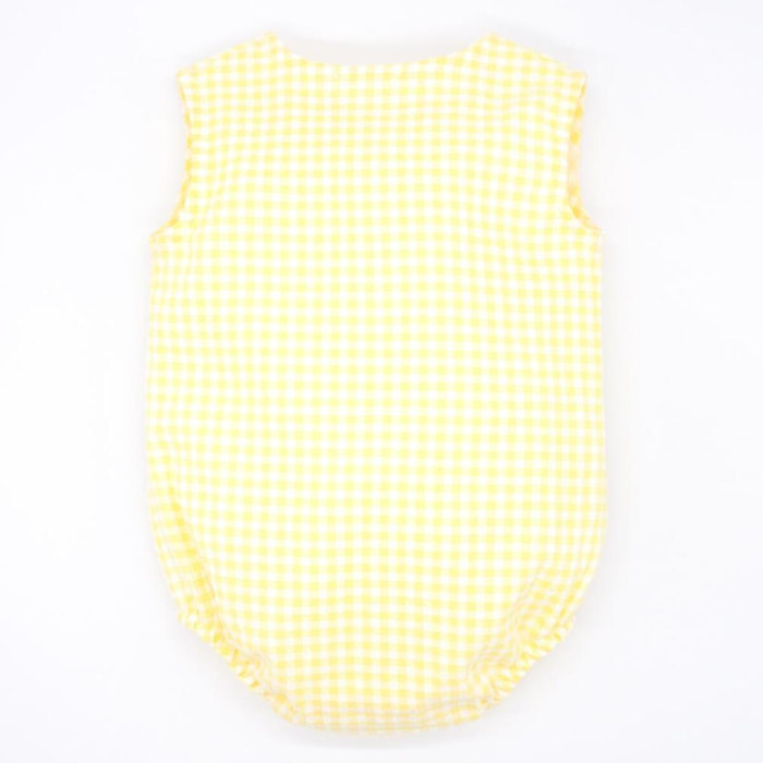 Pelele de vichy amarillo. Con bolsillo y tapeta con botones en el delantero. Goma en las piernas.