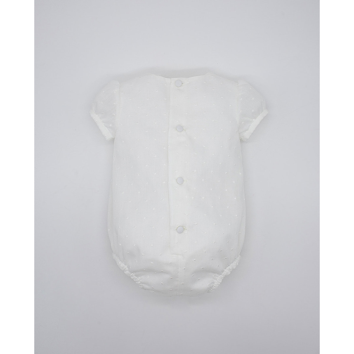 Pelele de muselina bordada blanca, de manga corta. Con puntilla y fruncido en el pecho.