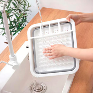 Escurridor de platos plegable con orificios en la base, diseñado para secar y organizar utensilios de cocina de forma práctica.