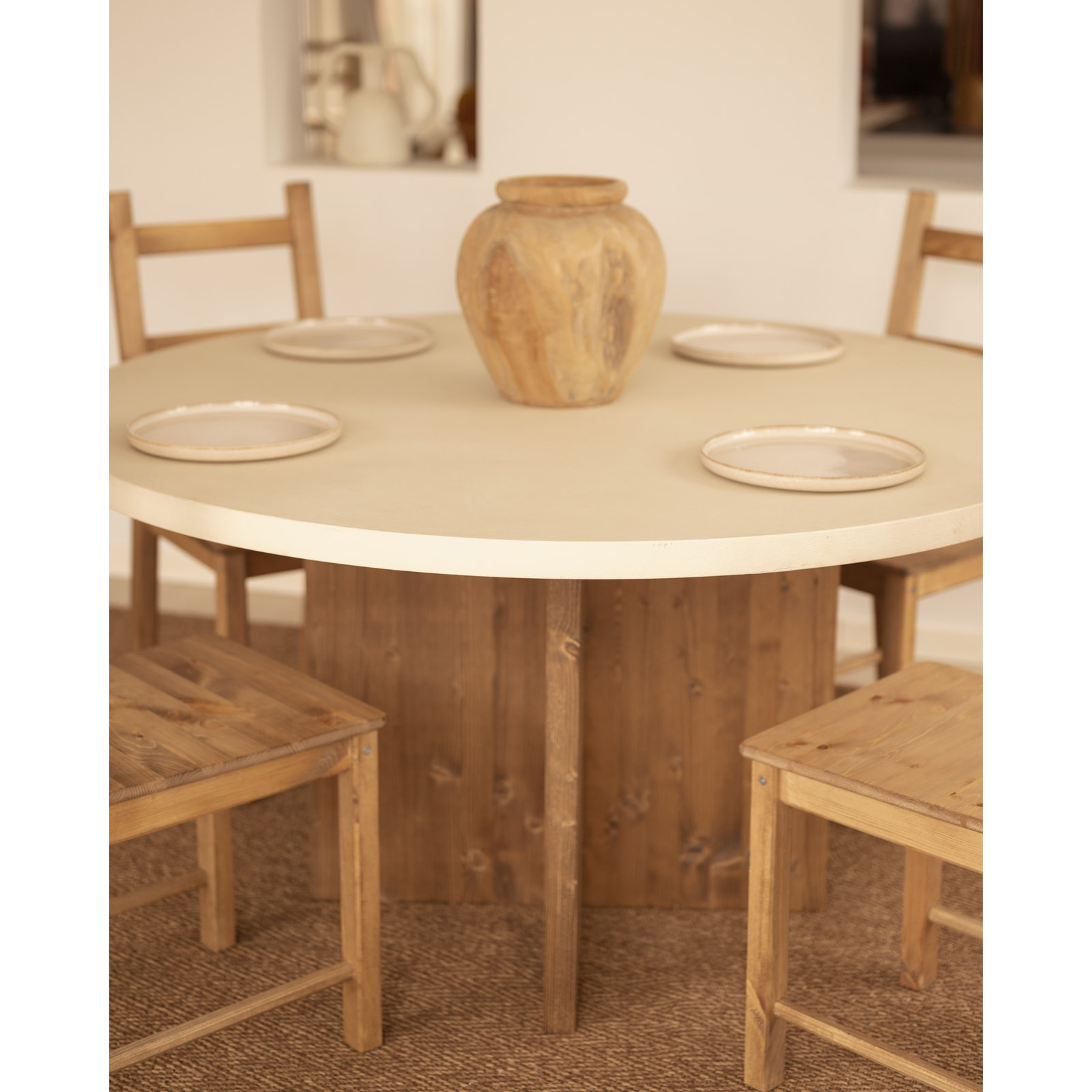 Table de salle à manger ronde en microciment de couleur blanc cassé avec des pieds en bois de chêne foncé en plusieurs tailles