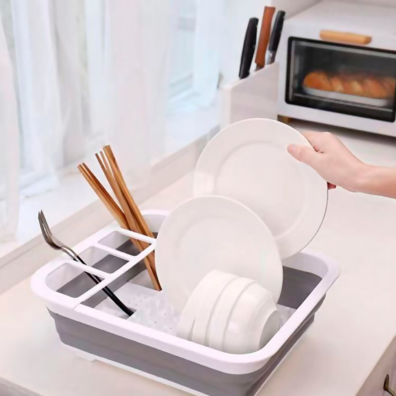Escurridor de platos plegable con orificios en la base, diseñado para secar y organizar utensilios de cocina de forma práctica.