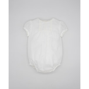 Pelele de muselina bordada blanca, de manga corta. Con puntilla y fruncido en el pecho.