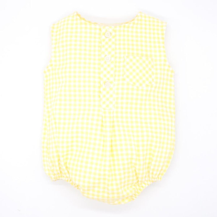 Pelele de vichy amarillo. Con bolsillo y tapeta con botones en el delantero. Goma en las piernas.