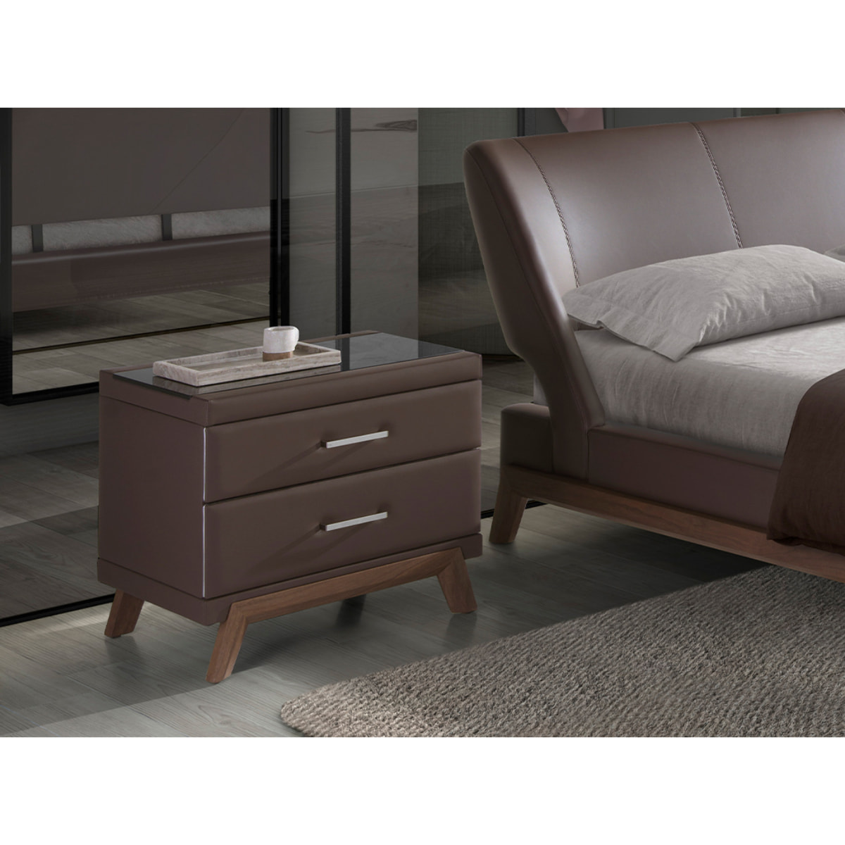 Mesita de noche Angel Cerdá con estructura de madera chapada en nogal natural tapizada en polipiel marrón chocolate y patas de madera chapada en nogal natural tapa de cristal templado tintado en negro 60x46x56cm