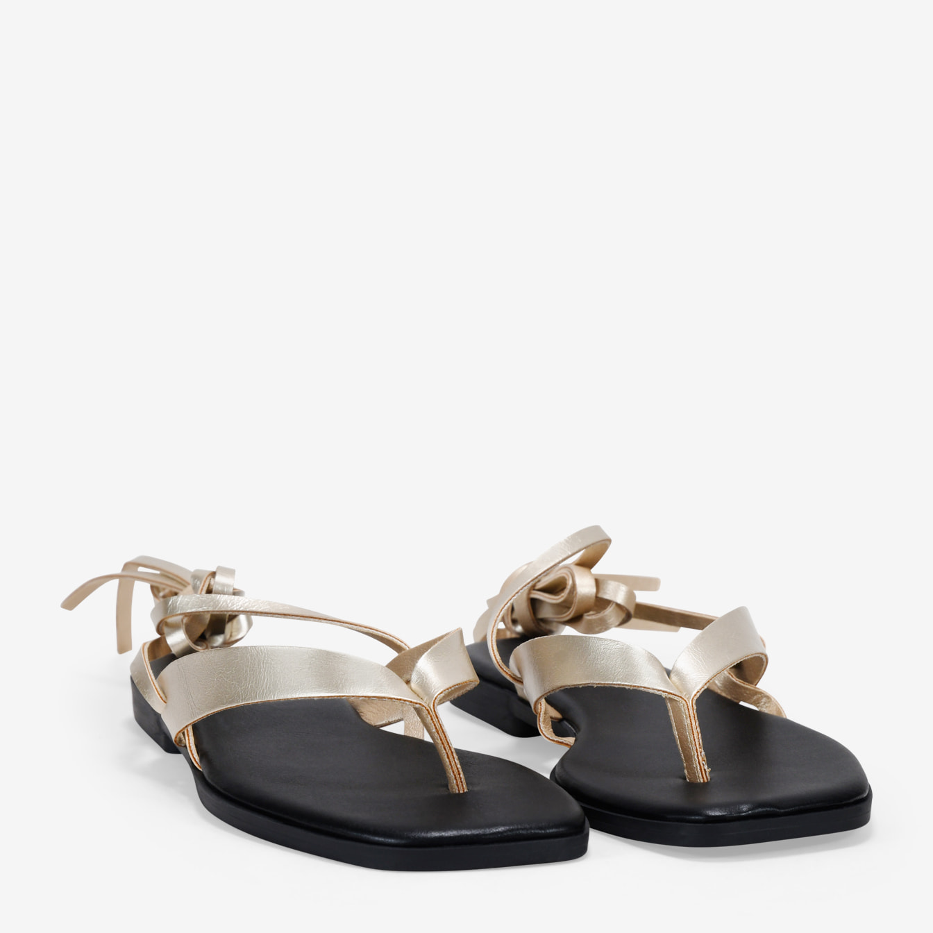 Sandalias de dedo doradas con tiras atadas