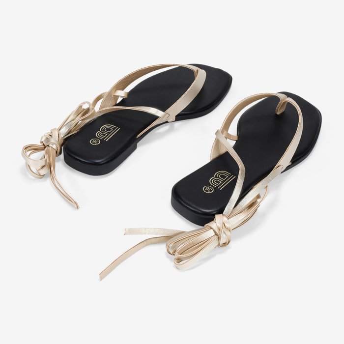 Sandalias de dedo doradas con tiras atadas