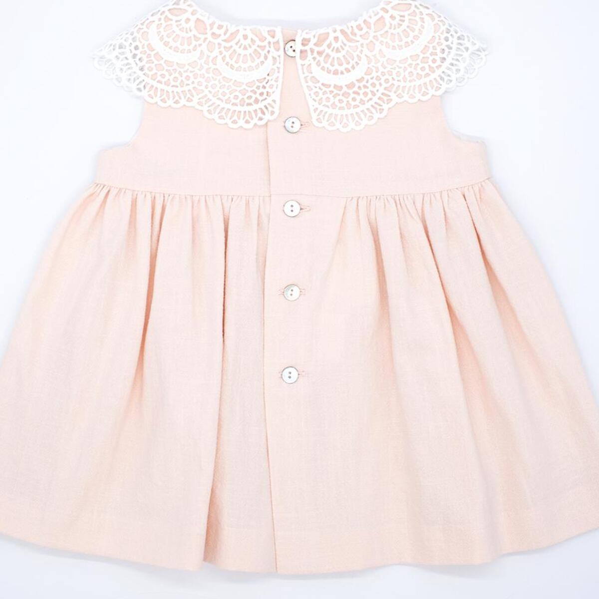 Vestido corto rosa, falda fluncida y cuello de guipur blanco.