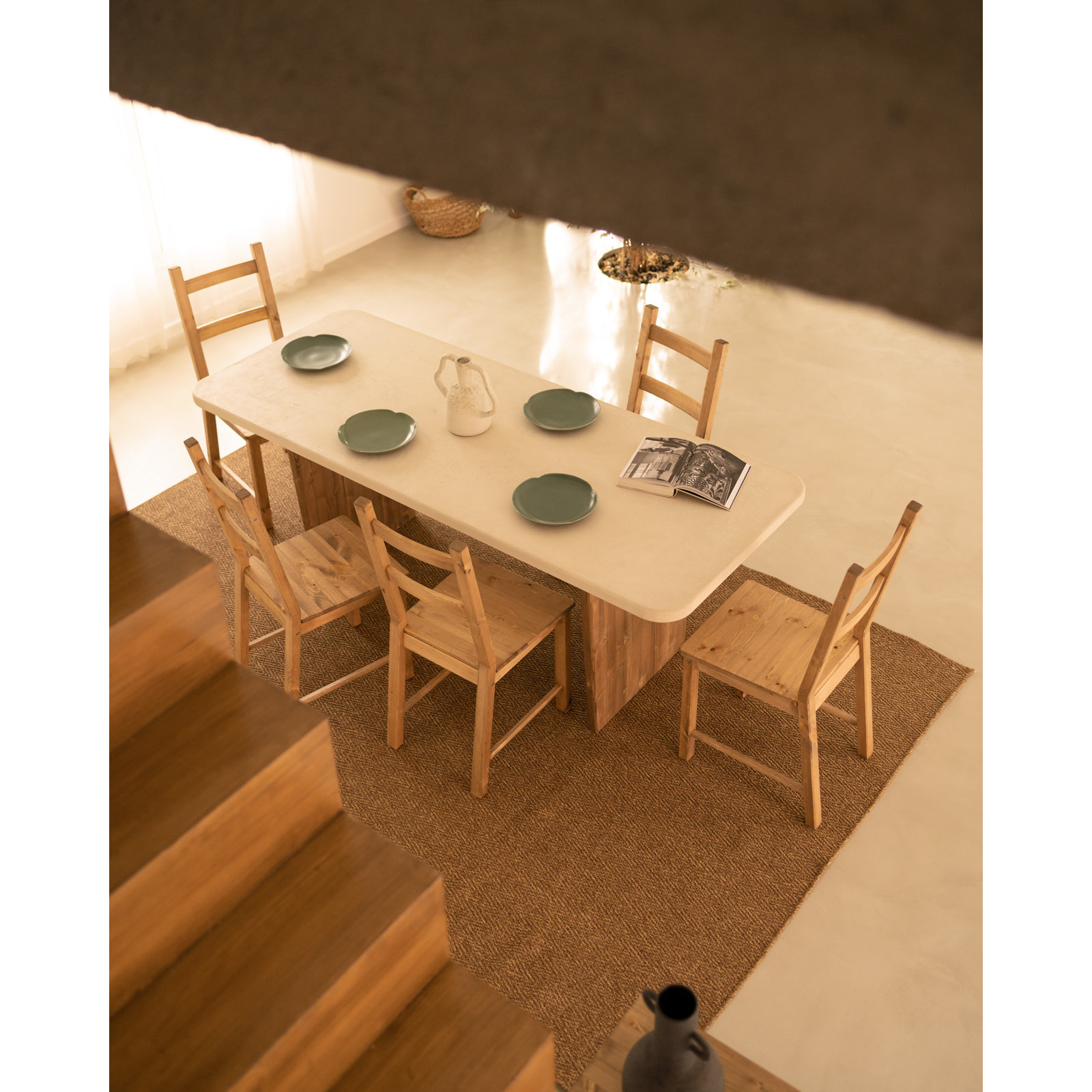 Table de salle à manger en microciment de couleur blanc cassé avec des pieds en bois de chêne foncé en différentes tailles