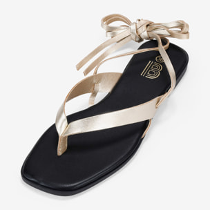 Sandalias de dedo doradas con tiras atadas
