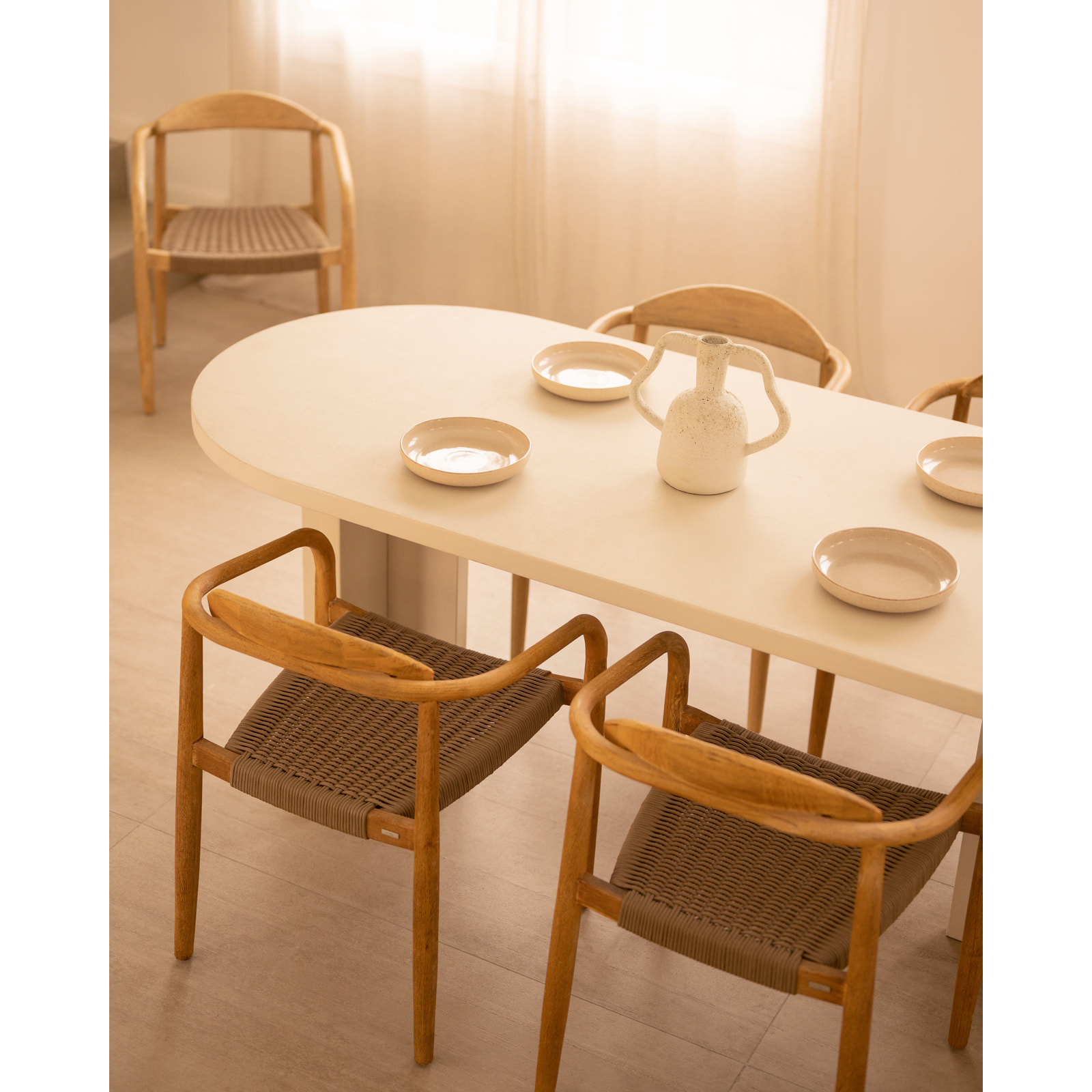 Table de salle à manger ovale en microciment de teinte blanc cassé disponible en différentes tailles