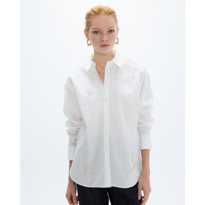 Camicia oversize con borchie dorate e disegni posizionati strategicamente.