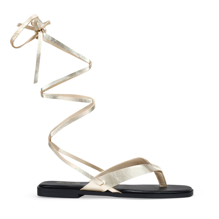 Sandalias de dedo doradas con tiras atadas