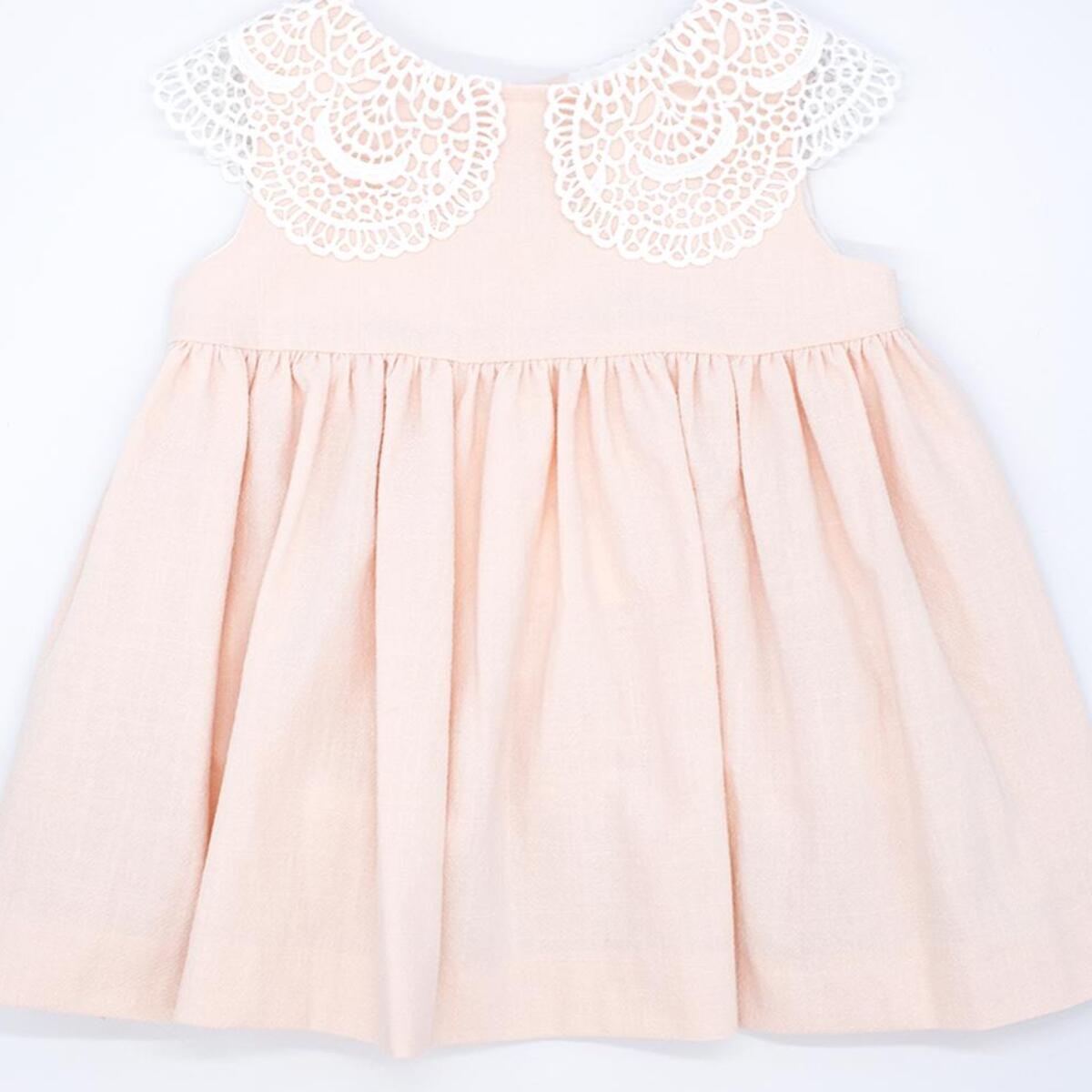 Vestido corto rosa, falda fluncida y cuello de guipur blanco.