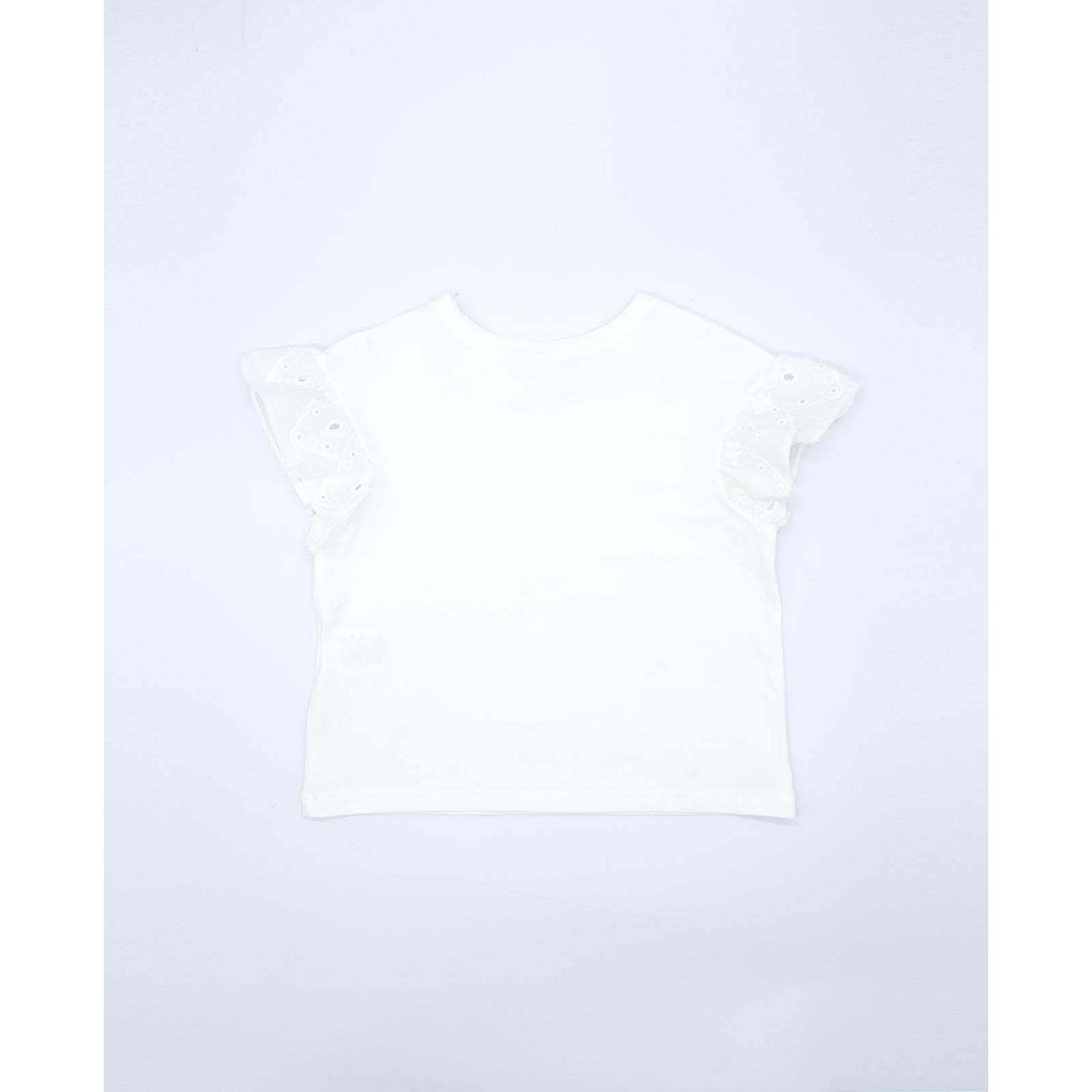 Camiseta blanca con volantes blancos bordados en las sisas.