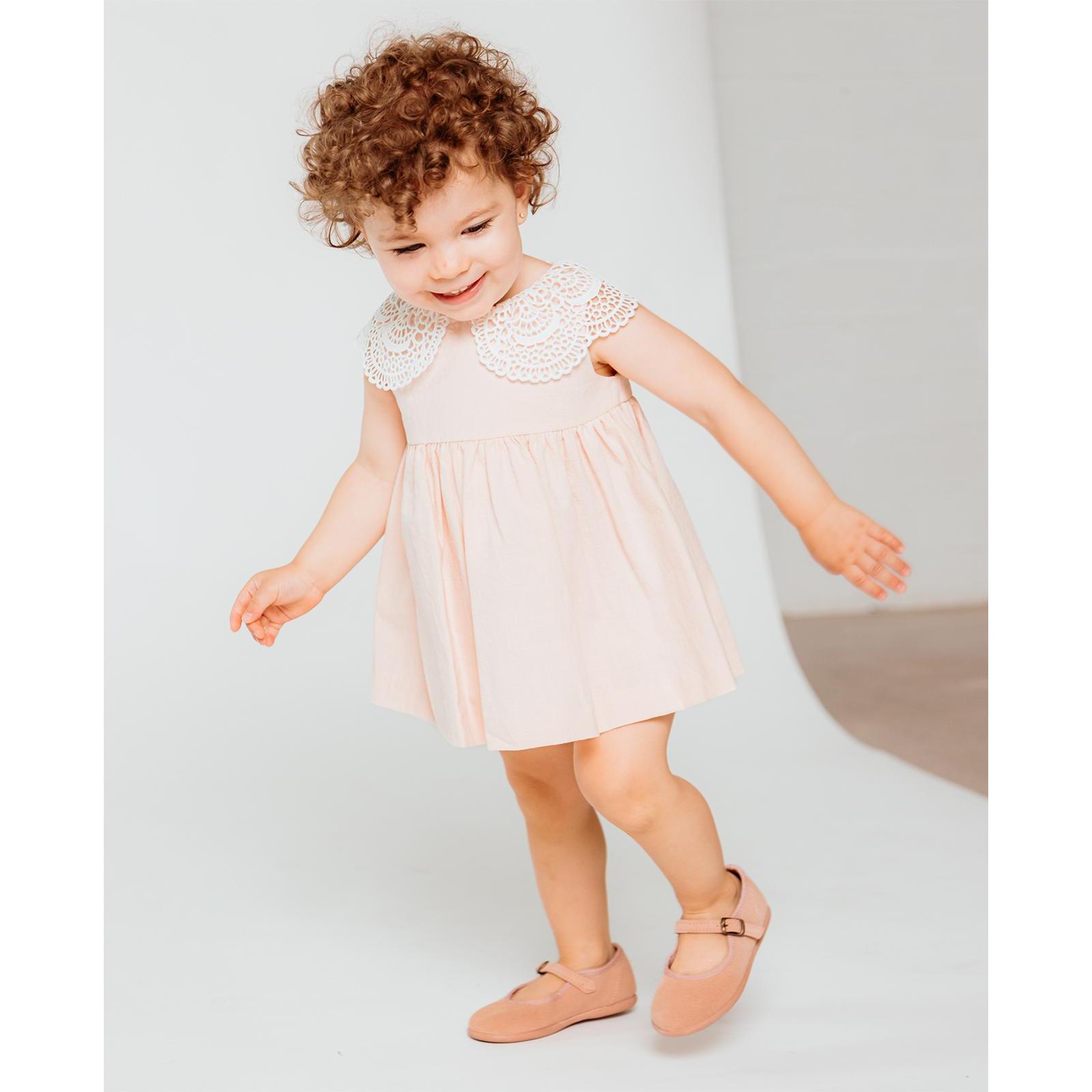 Vestido corto rosa, falda fluncida y cuello de guipur blanco.