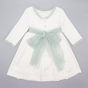 Vestido de pique blanco, con volantes en cuello y puños, y lazada en tul verde.
