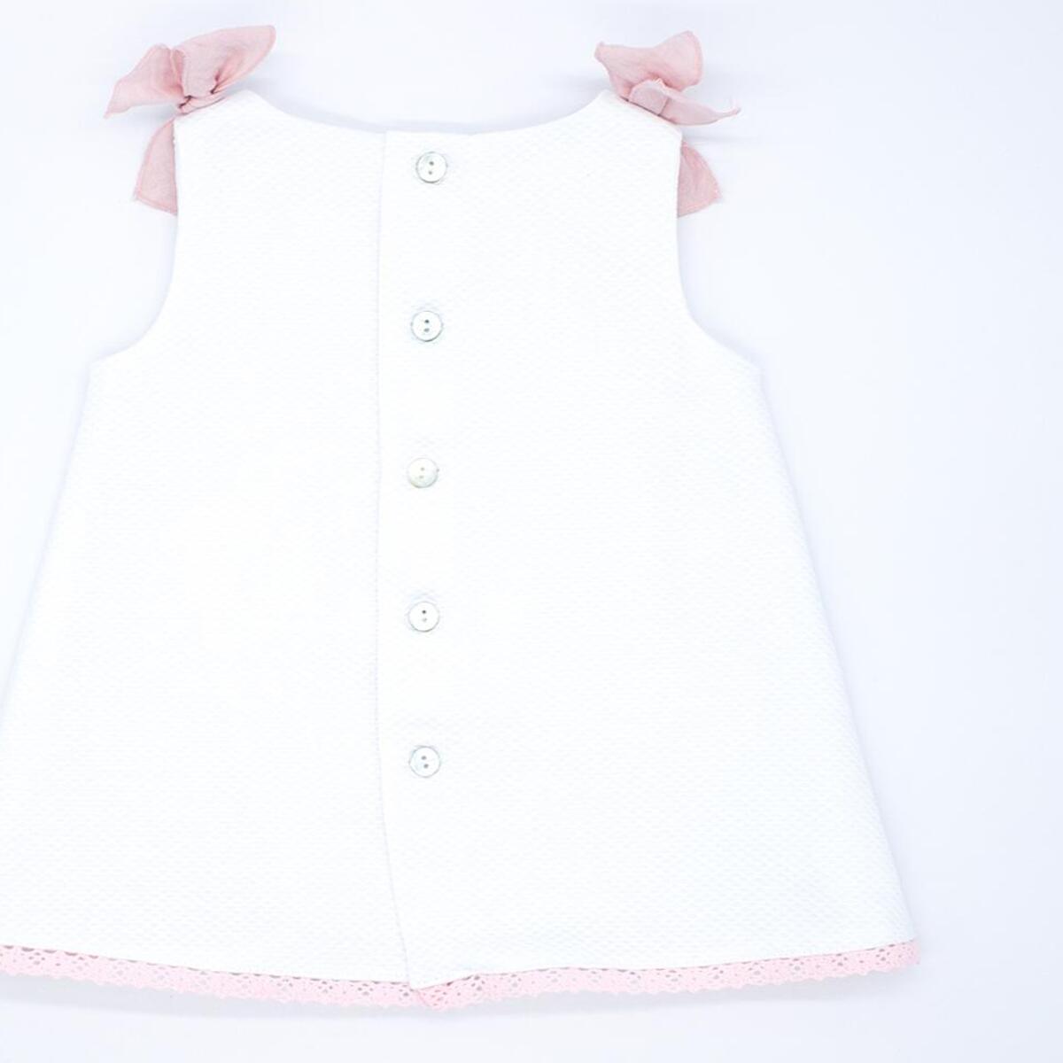 Vestido de piqué blanco con detalle de puntillas rosas.