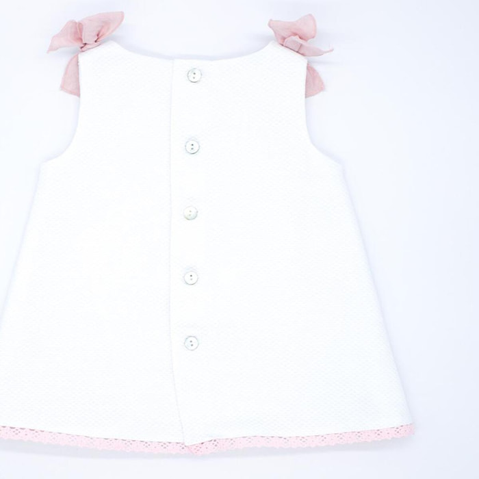 Vestido de piqué blanco con detalle de puntillas rosas.