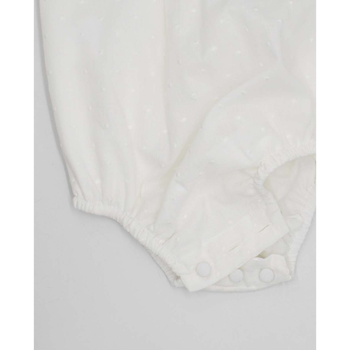 Pelele de muselina bordada blanca, de manga corta. Con puntilla y fruncido en el pecho.