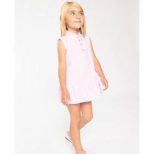 Vestido de polo rosa, sin mangas con volante en el cuello y en el bajo.