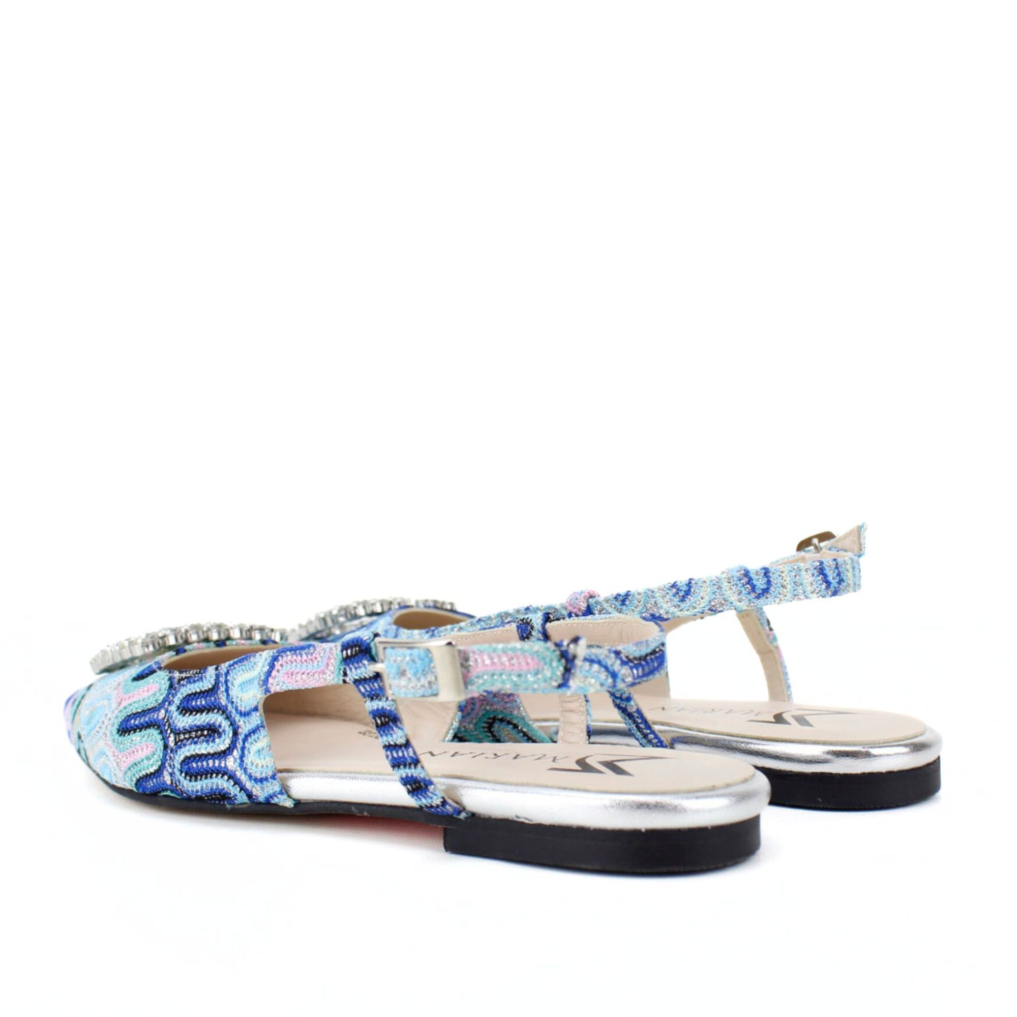 Mule fabricado en tejido estampado en tonos azul cielo. Detalle adorno joya pedrería. Tacón 1 cm