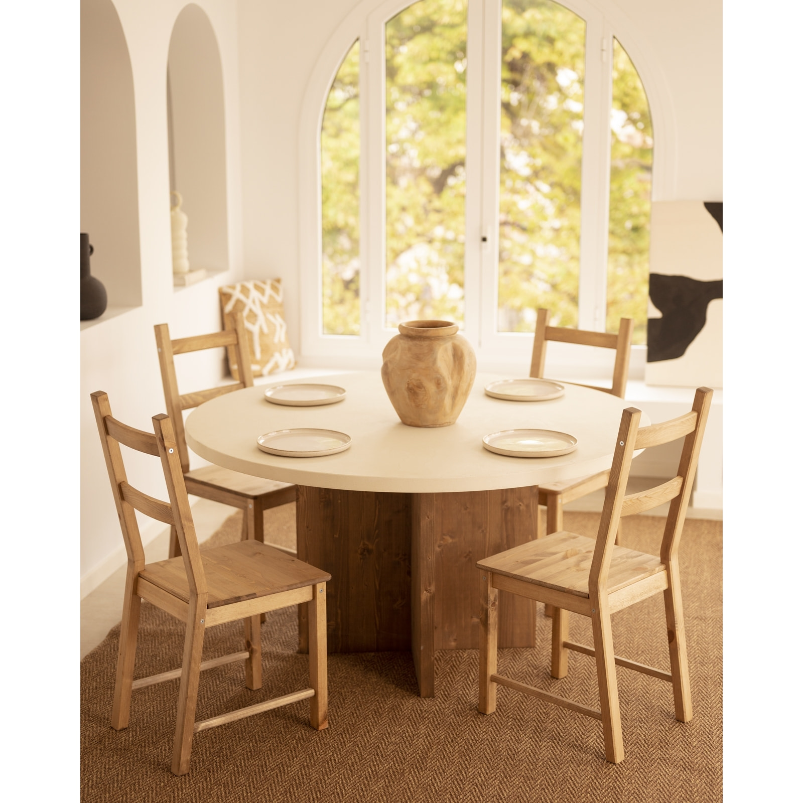 Mesa de comedor redonda de microcemento en tono blanco roto con patas de madera tono roble oscuro en varias medidas