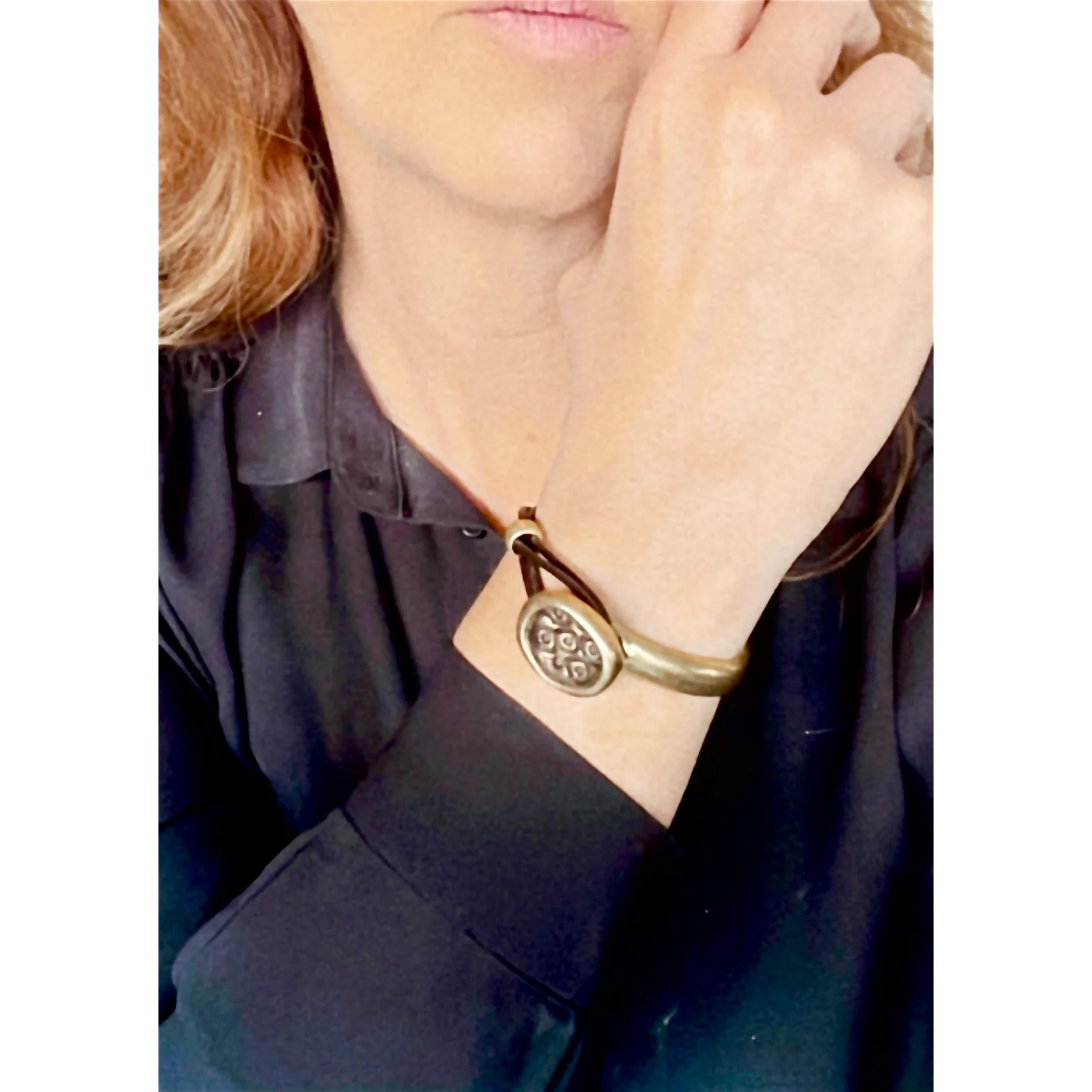 Pulsera media rá­gida en botón grabado y cuero marrón con metal dorado