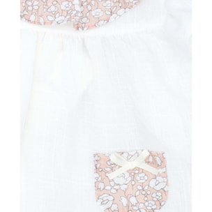 Blusa blanca con bolsillos y volante en el cuello de flores rosas, volantes en las sisas. Lazo en el bolsillo.