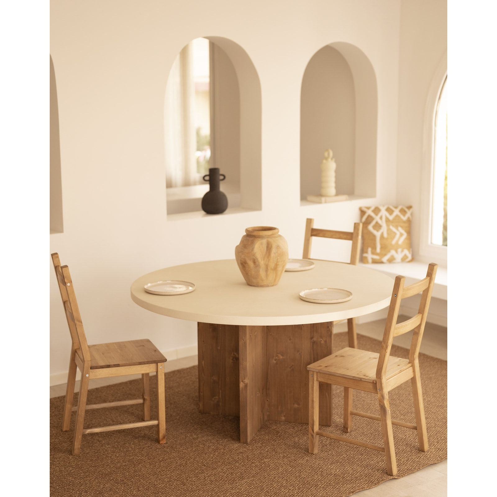 Table de salle à manger ronde en microciment de couleur blanc cassé avec des pieds en bois de chêne foncé en plusieurs tailles