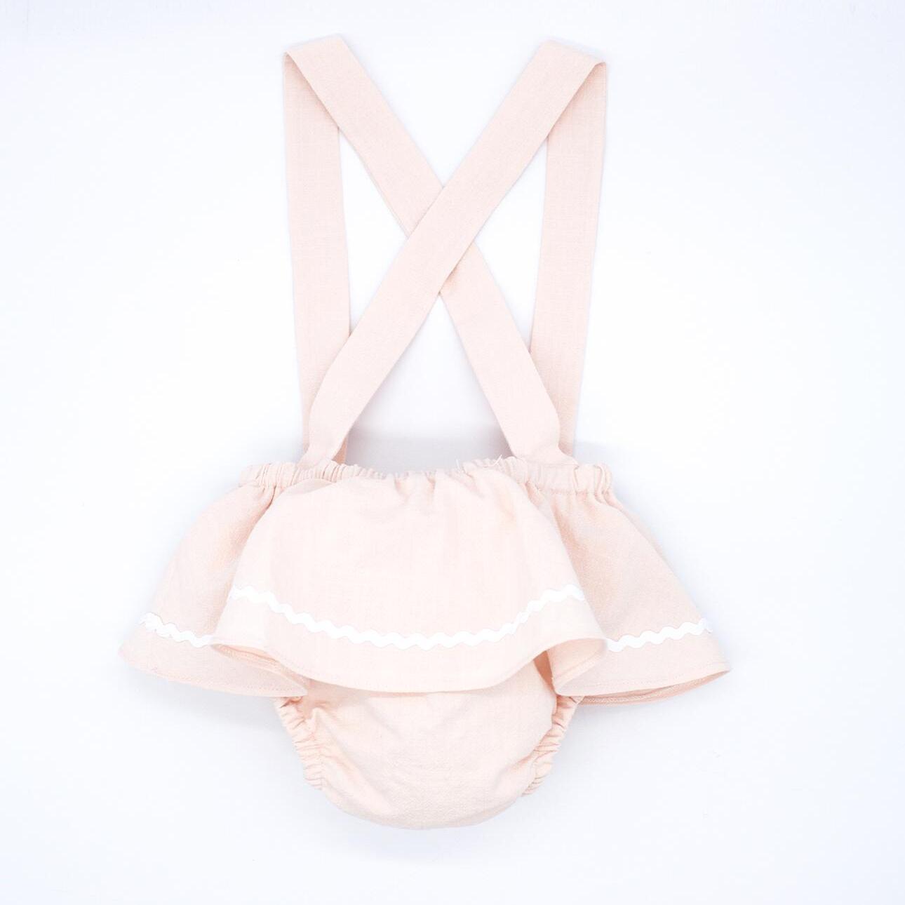 Cubrepañal rosa, con tirantes y falda con picunela.