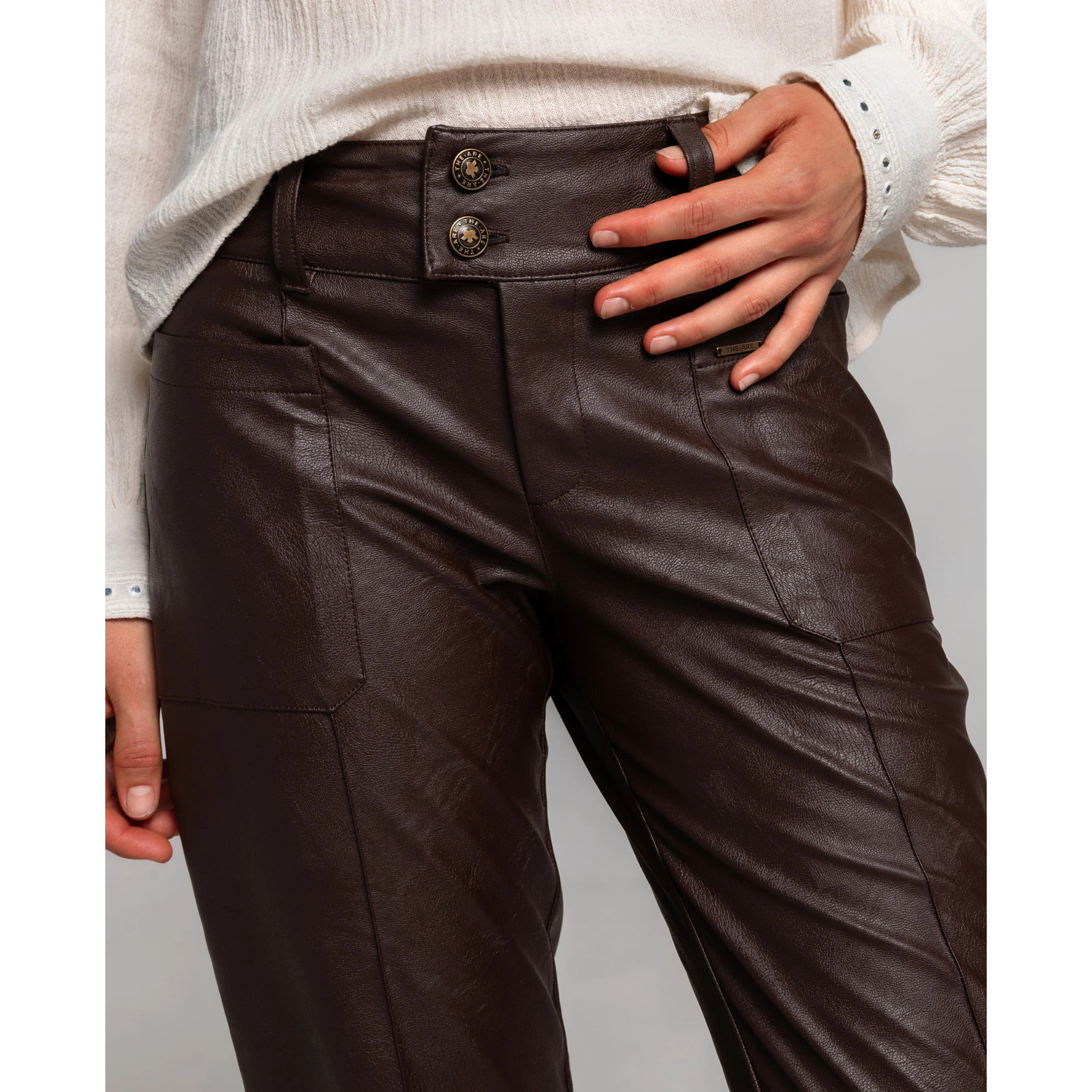 Pantalón de polipiel marrón con bragueta, doble botón y bolsillos.