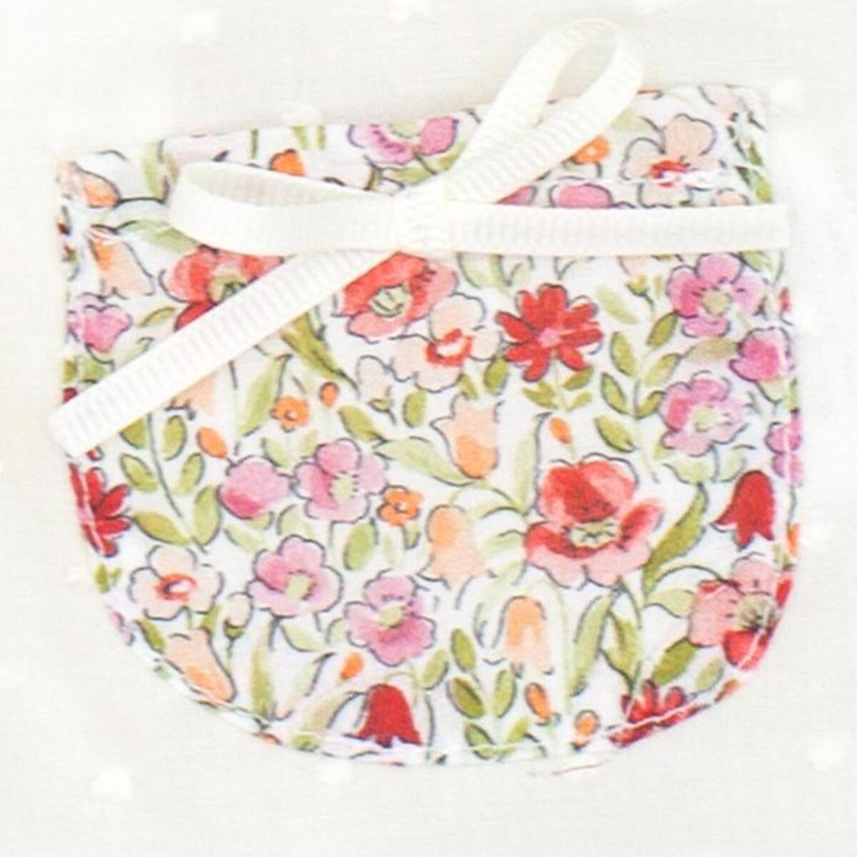 Blusa blanca con bolsillos y volante en el cuello de flores rojas, volantes en las sisas. Lazo en el bolsillo.