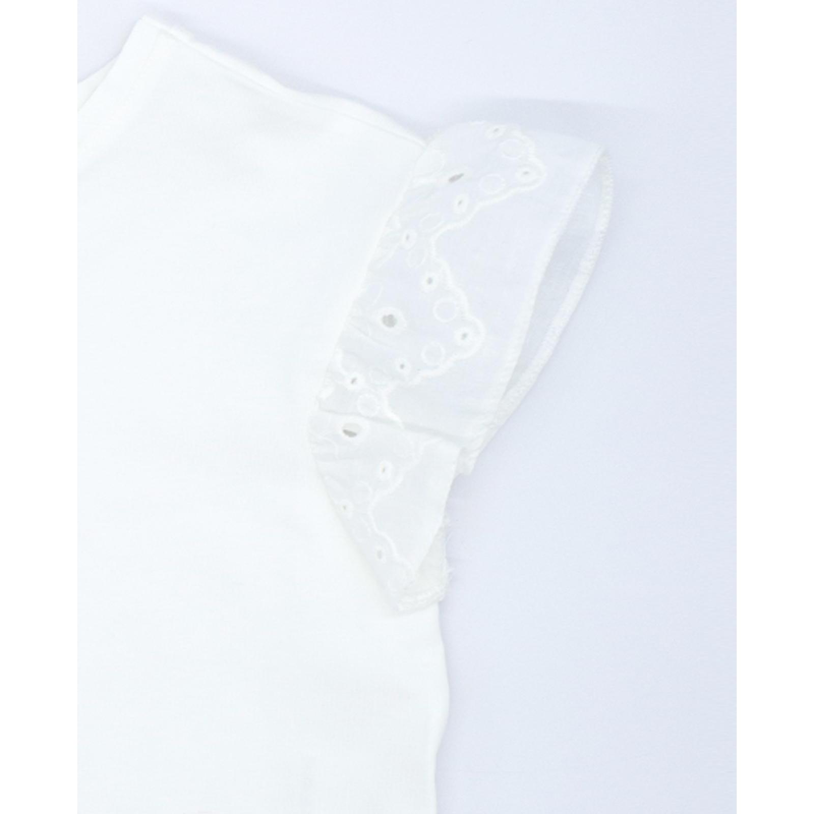 Camiseta blanca con volantes blancos bordados en las sisas.