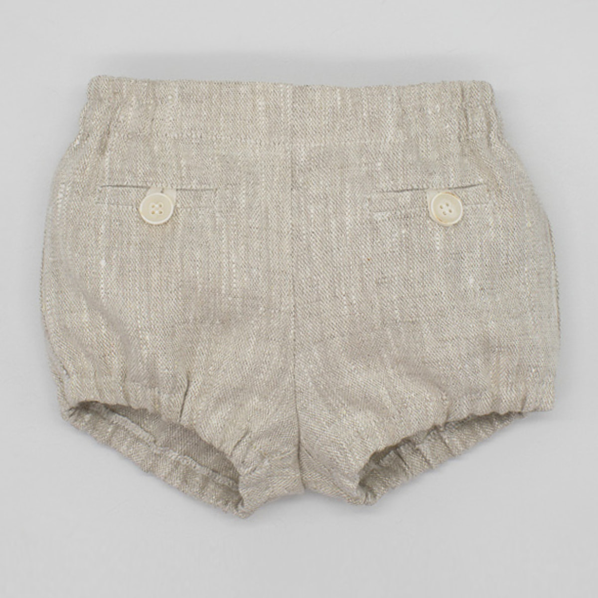 Bermuda corta de lino beige. Con falsos bolsillos y botones. Cintura y piernas elasticas.